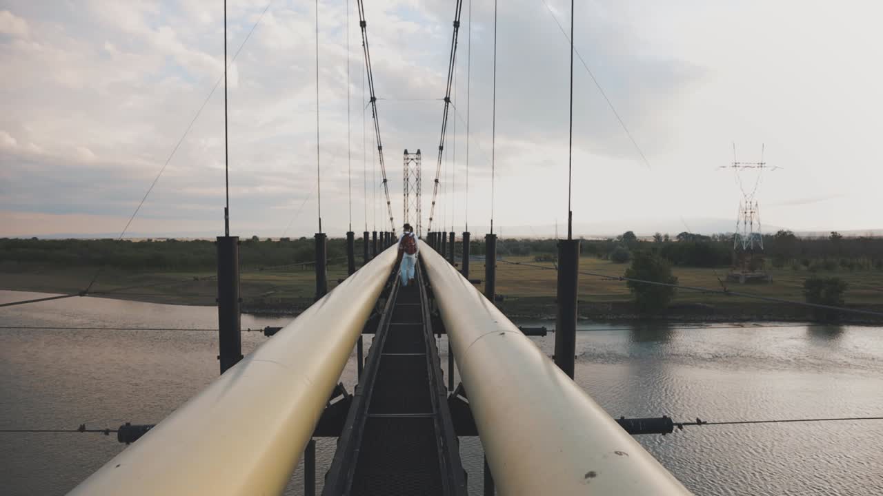 gente caminando sobre un puente colgante que cruza el río en un día nublado