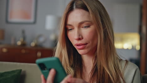 amazed woman reading smartphone message feeling success at home couch close up.