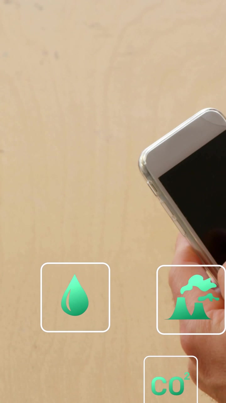 Vídeo vertical: Mão direita tocando no ícone de CO2 no telefone sobre uma mesa de madeira, focando no CO2 e selecionando a opção eco.