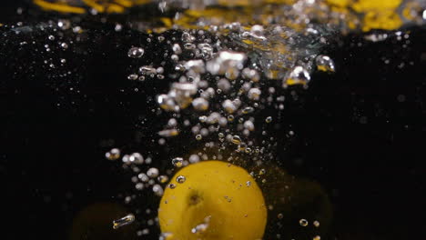 Many-Citrus-Lemons-Splash-in-Water-with-Bubbles-in-Slow-Motion