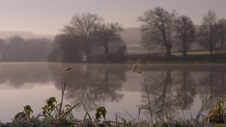 Stunning shot of a glassy calm lake early in the morning, with focus pull