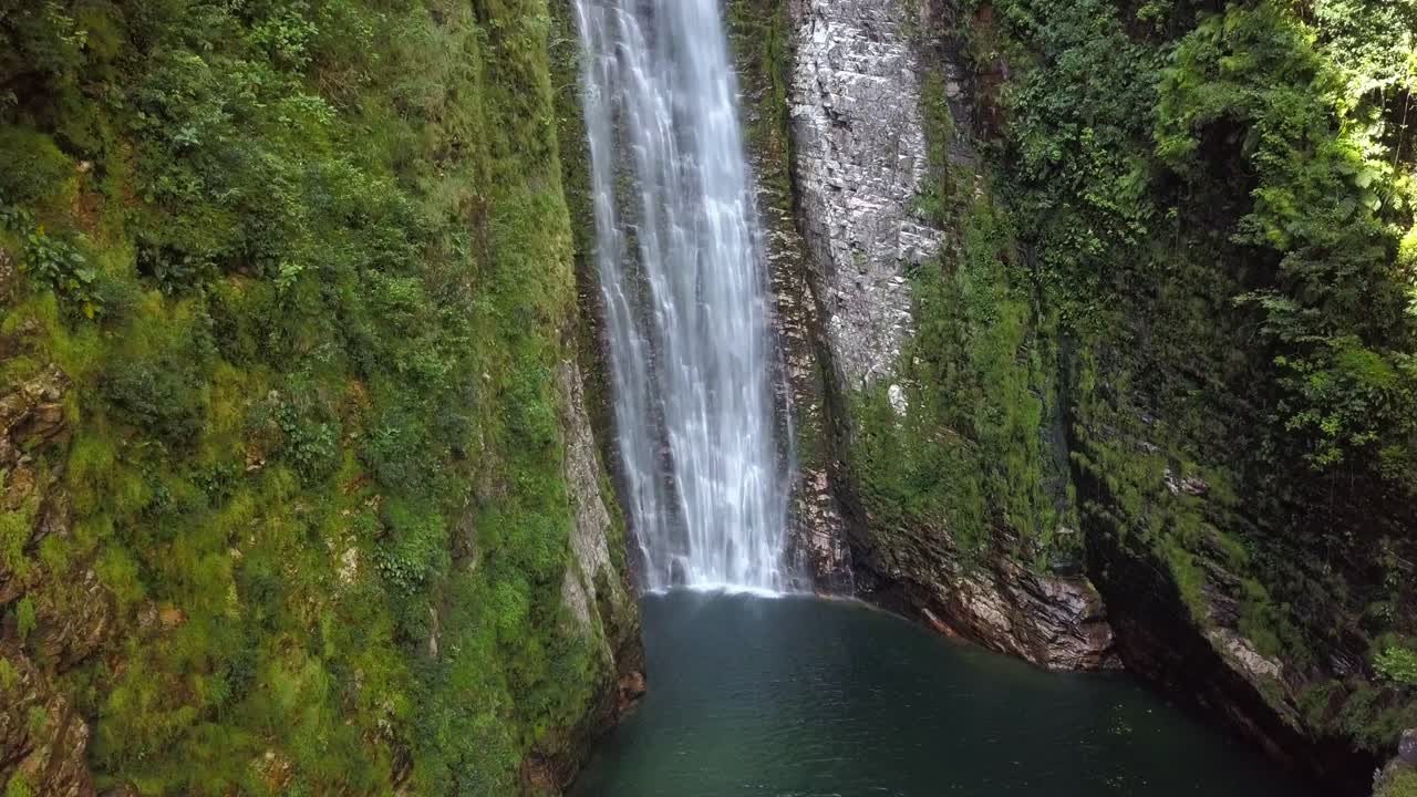 Aerial drone shot tilting down, showcasing the breathtaking Segredo waterfall amidst the natural beauty of Chapada dos Veadeiros, Brazil