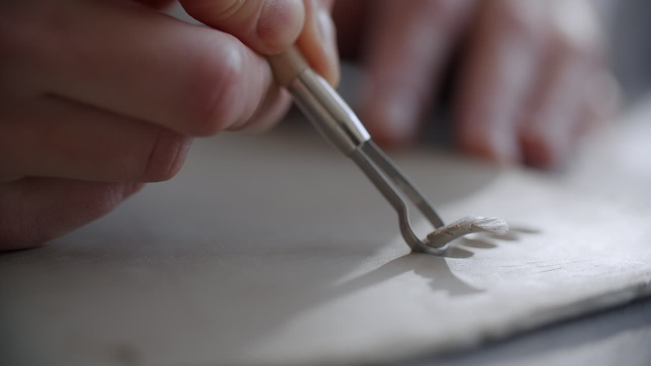Close-up of a potter using a tool to sculpt clay