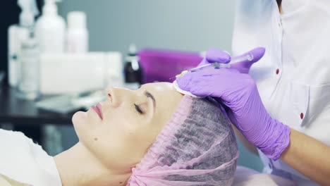 cosmetologist makes the rejuvenating facial injections procedure on the face skin in a beauty salon