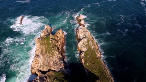 aerial top down natural seascape rock formation waves crashing over the cliff