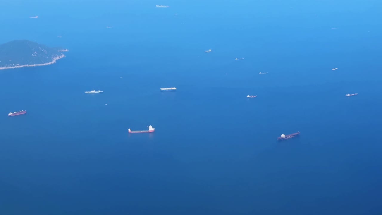Aerial view of cargo ships on vast blue sea under clear sky