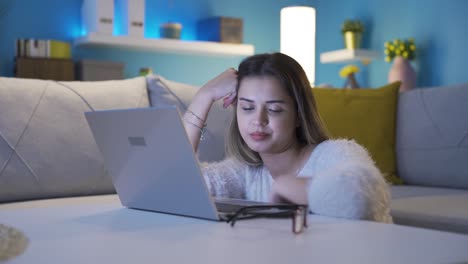 mujer joven somnolienta y agotada mirando la computadora portátil.