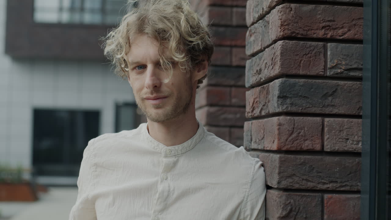 Young man leaning against a brick wall