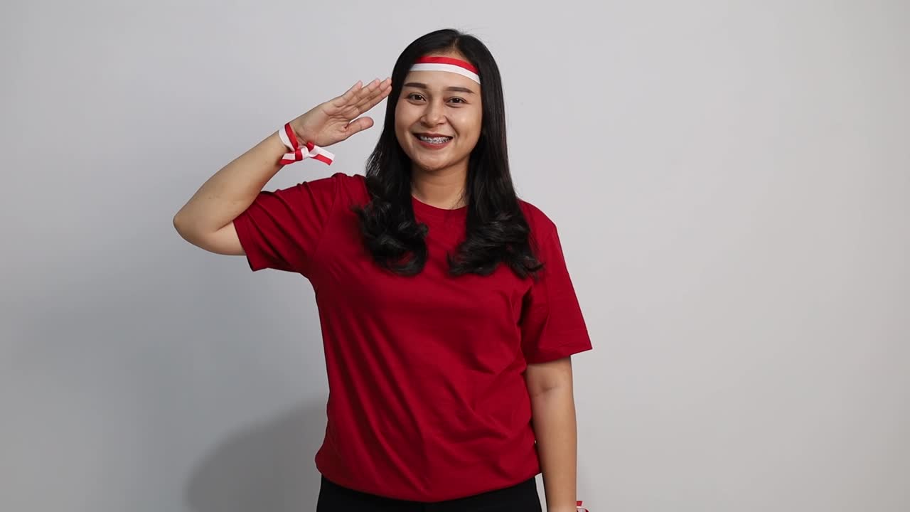 Pretty Asian woman giving salute celebrate Indonesian independence day on 17 August isolated over white background