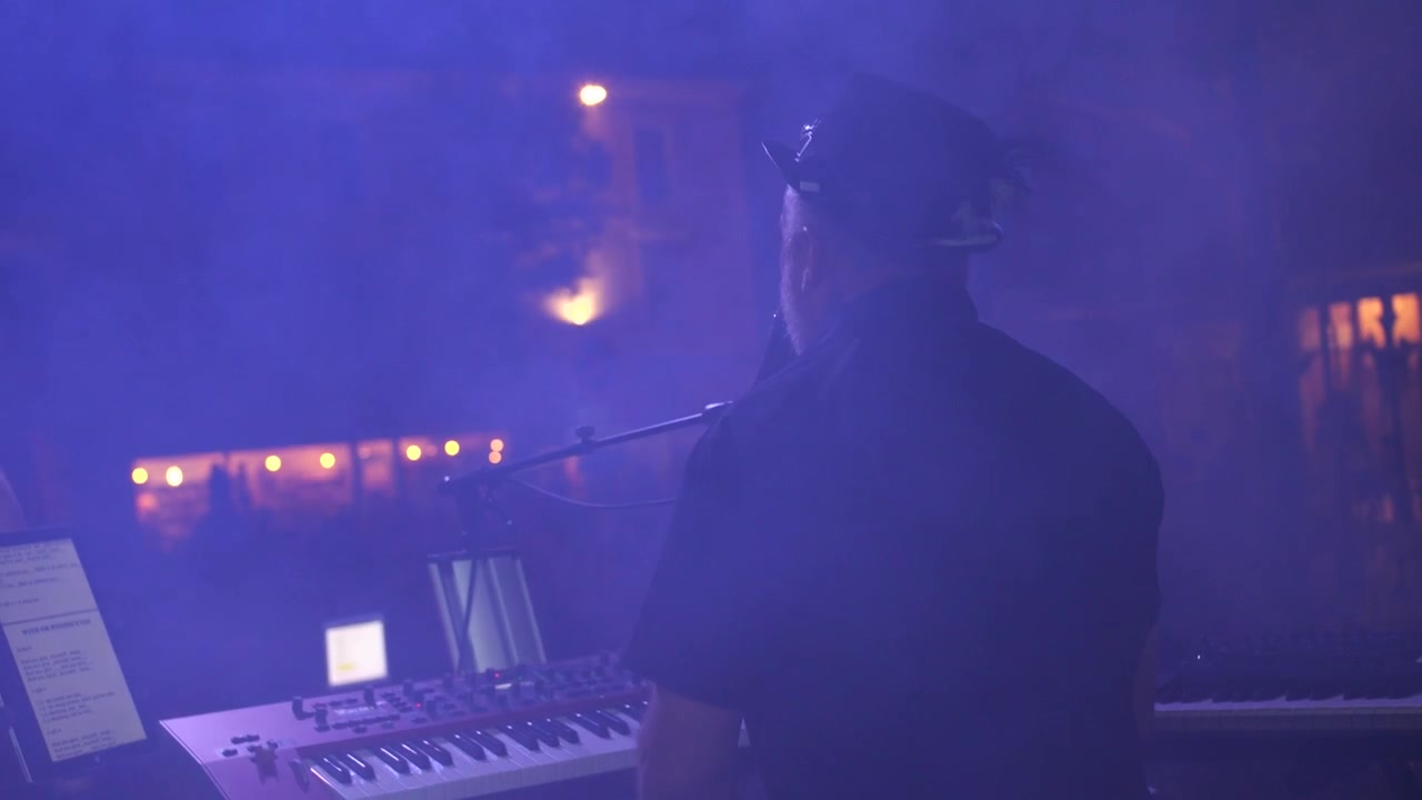 Ripresa a mano di un artista che si esibisce su un palco mentre canta e suona il pianoforte.