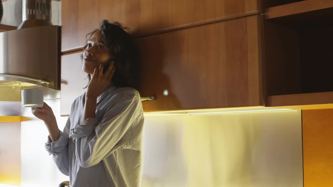 Woman leaning in kitchen speaking on phone while holding mug starting network overlay for smarttech