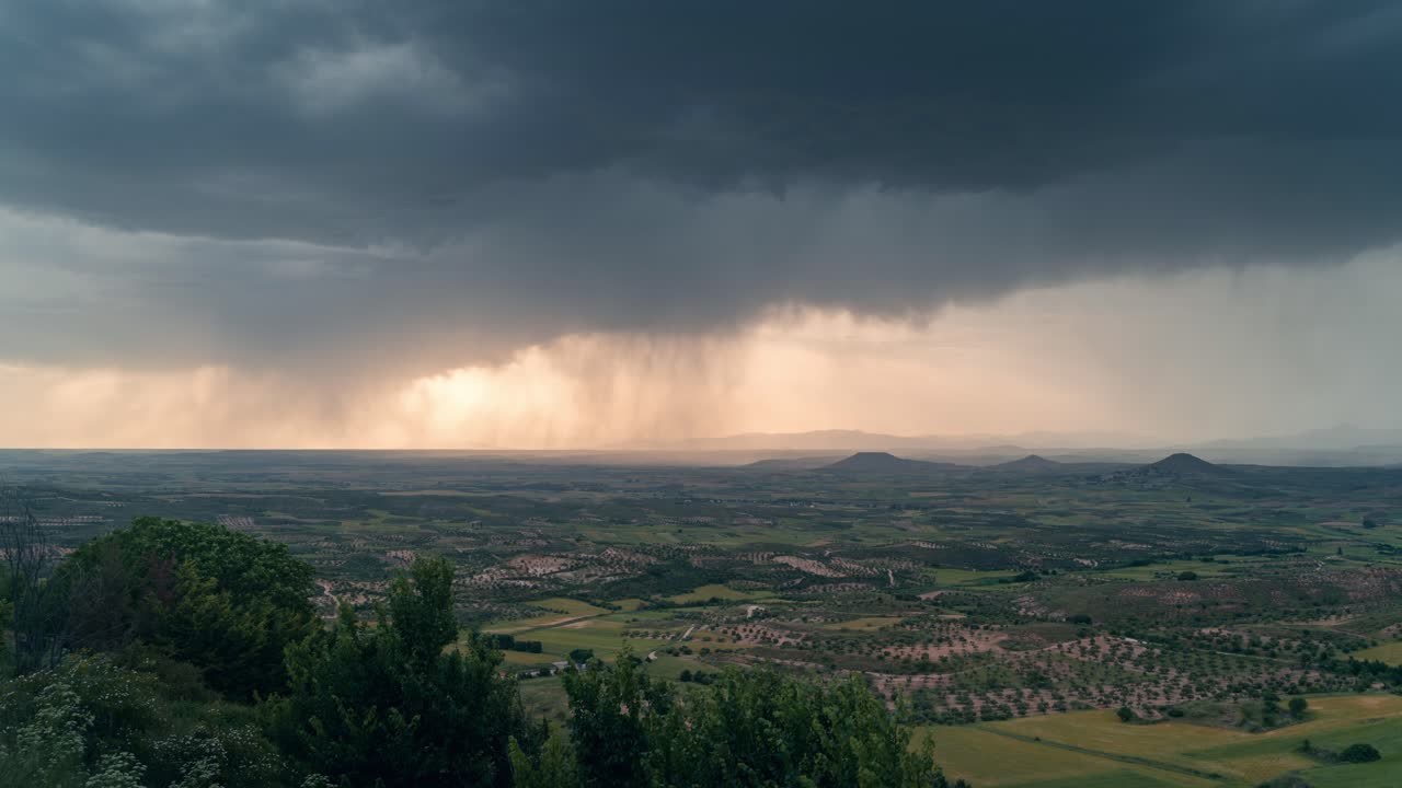 Dramatic view of La Alcarria plains from a viewpoint during a powerful storm, with rain curtains and dark clouds sweeping across the landscape