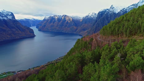 Aerial-fly-over-bridge-revealing-lush-mountains-and-snow-top-mountains-over-the-lake-in-Norway-alesund