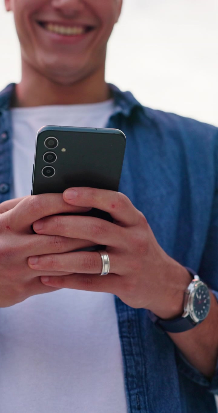 Giovane sorridente che usa lo smartphone all'aperto