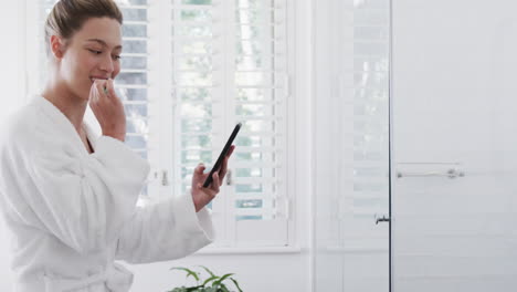 Mujer-Birracial-Feliz-Cepillándose-Los-Dientes-Usando-Un-Teléfono-Inteligente-En-El-Baño,-Cámara-Lenta