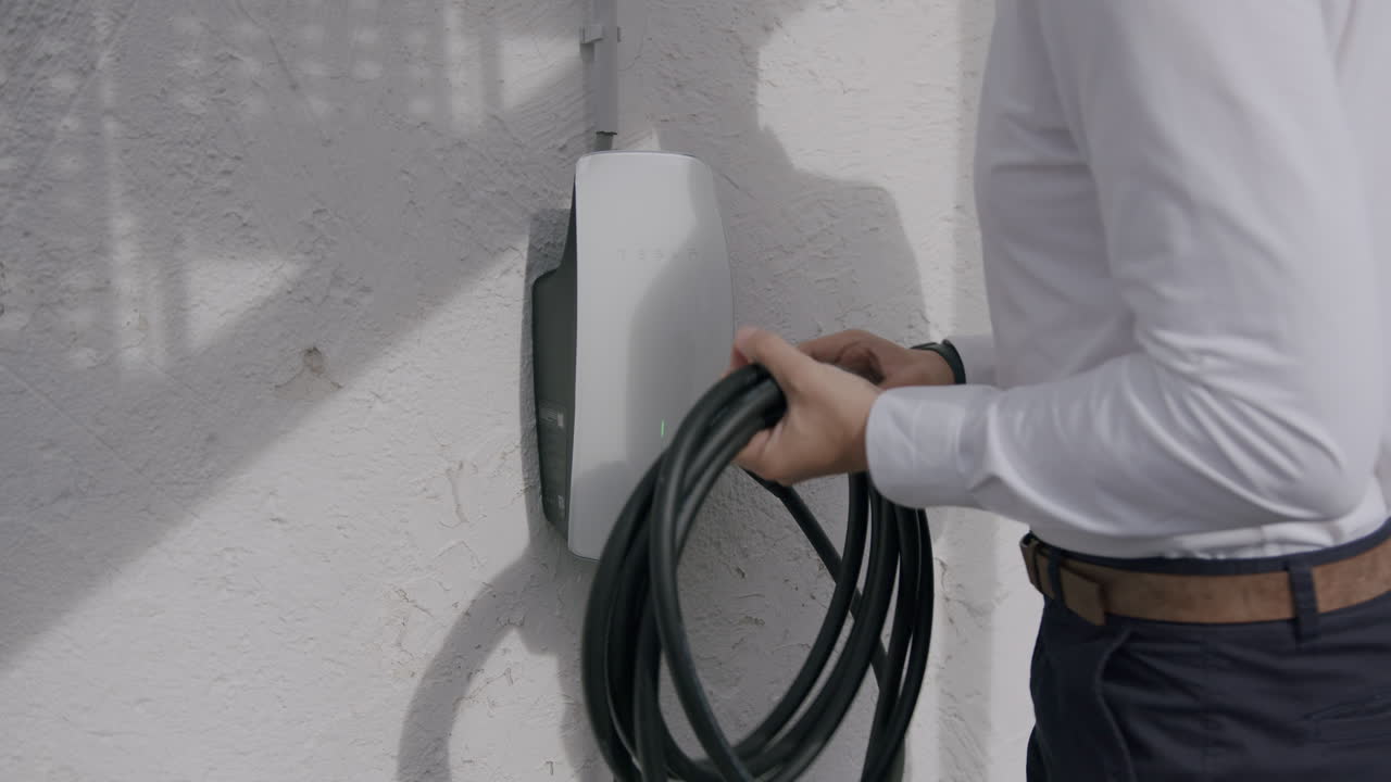 tomando el cable de carga de la caja de pared privada para cargar un tesla