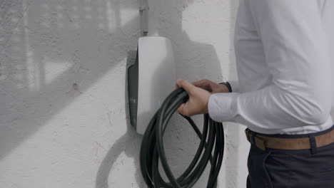 taking-charging-cable-from-the-private-wallbox-to-charge-a-Tesla