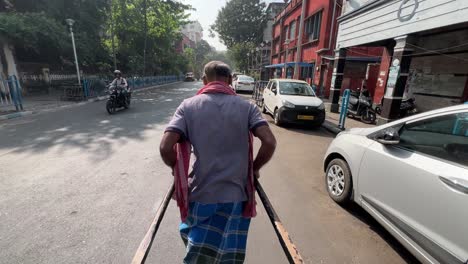 man pulling rickshaw on busy kolkata street