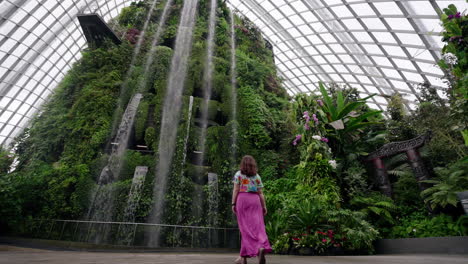cloud forest greenhouse with a female tourist wearing pink dress in gardens by the bay, singapore. low angle shot
