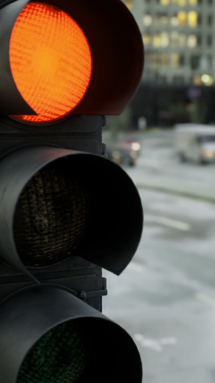 Traffic light signals caution during a rainy evening in a bustling city