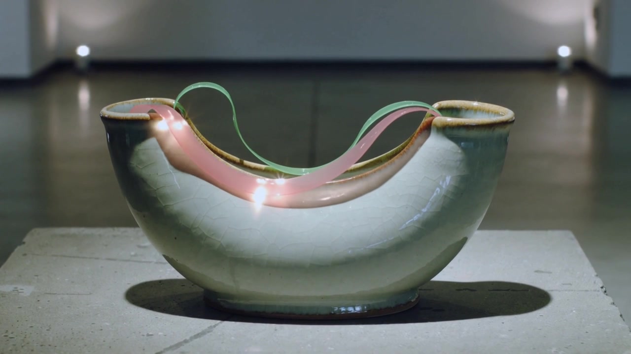 Starting motor moving green and pink bands across ceramic bowl on plinth at gallery