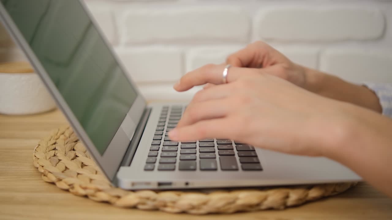 Close-up of the girl's hands typing text. Side view. Green laptop screen. Selective soft focus. Remote training.