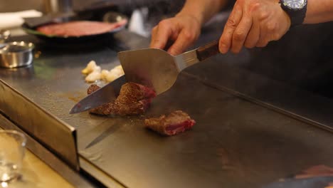 chef expertly prepares steak and shrimp on hot grill