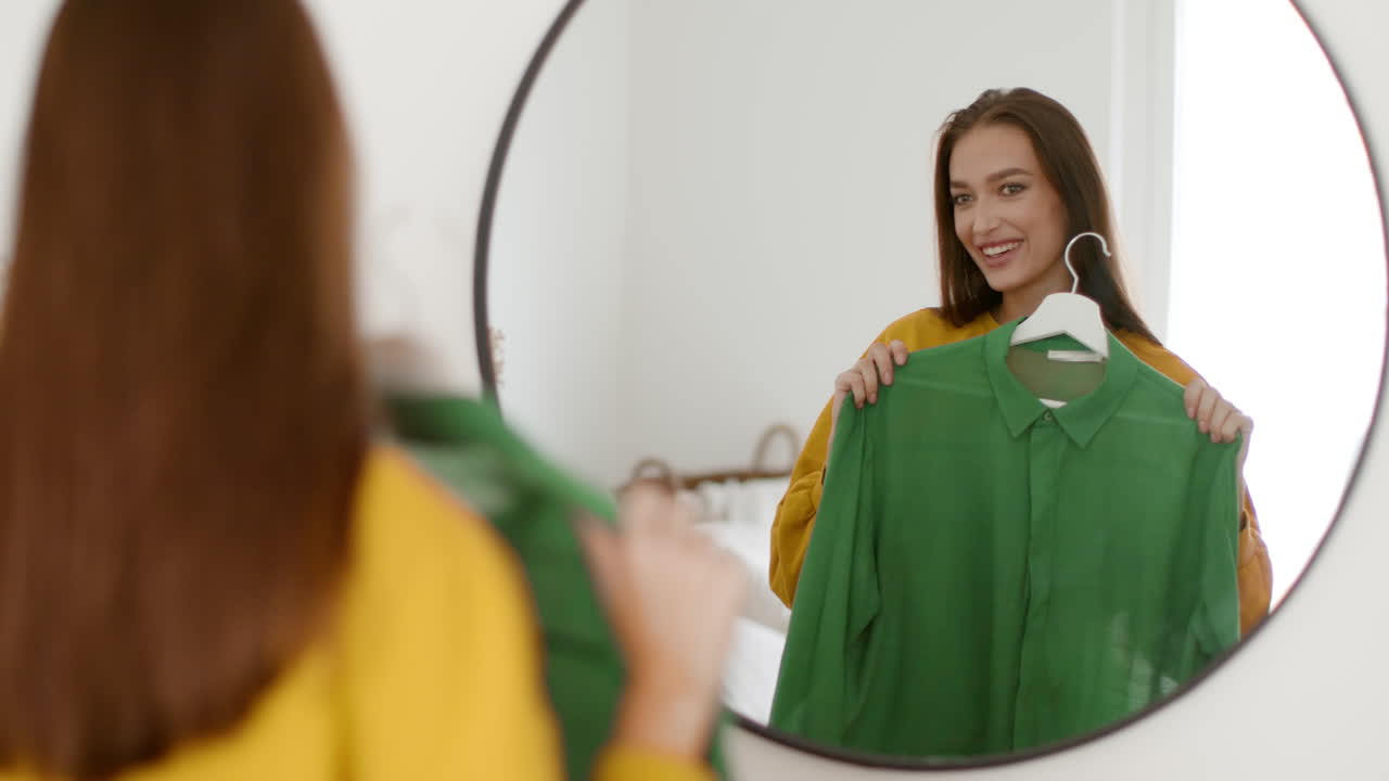 Woman Trying On a Green Shirt in Front of a Mirror