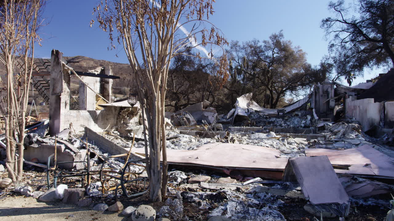 Panning shot of burned home surrounded by trees in Malibu, California. Woolsey Fire.