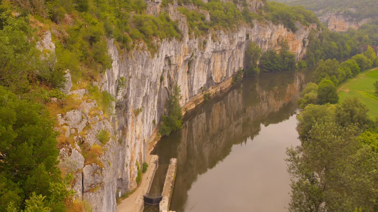 Path of Chemin de Halage along Lot river in Causses du Quercy UNESCO Geopark, France, surrounded by cliffs and greenery