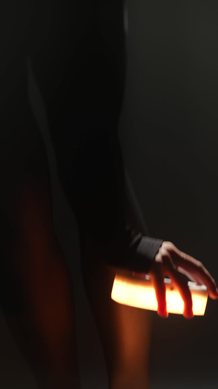 검은 양말을 입은 여자가 어두운 스튜디오에서 춤을 춘다