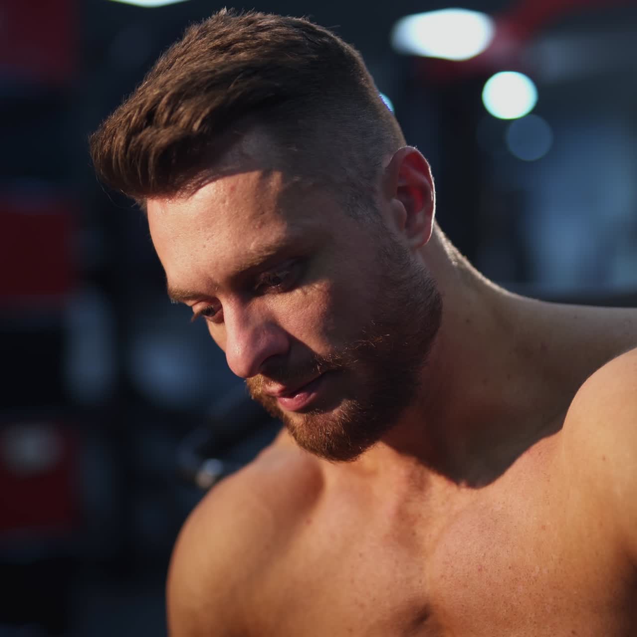 Sportsman drinking water. Sporty resting. Bearded guy having break after doing exercise on blur gym background. Handsome athletic man relax after training workout