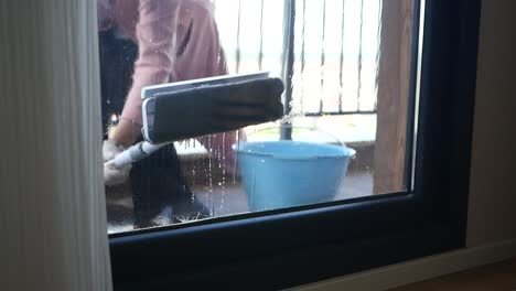 a woman cleaning a window with a mop and bucket