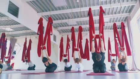 advanced group stretches leg muscles holding red hammocks