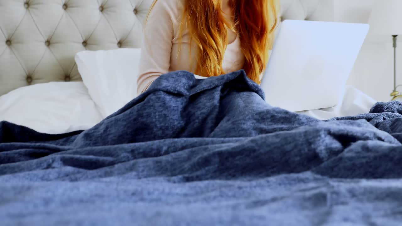 mujer hermosa usando computadora portátil mientras se relaja en la cama 4k