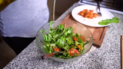 verter vinagreta en un bol de ensalada verde fresca en la encimera de la cocina