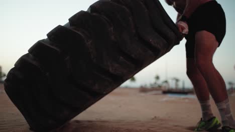 strong man training, doing workout lifting large tire in outdoor diy gym