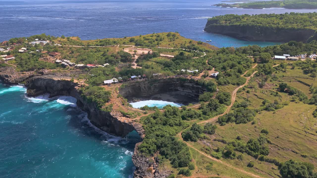 Aerial view of the natural rock arch and turquoise cove at Broken Beach on a sunny day