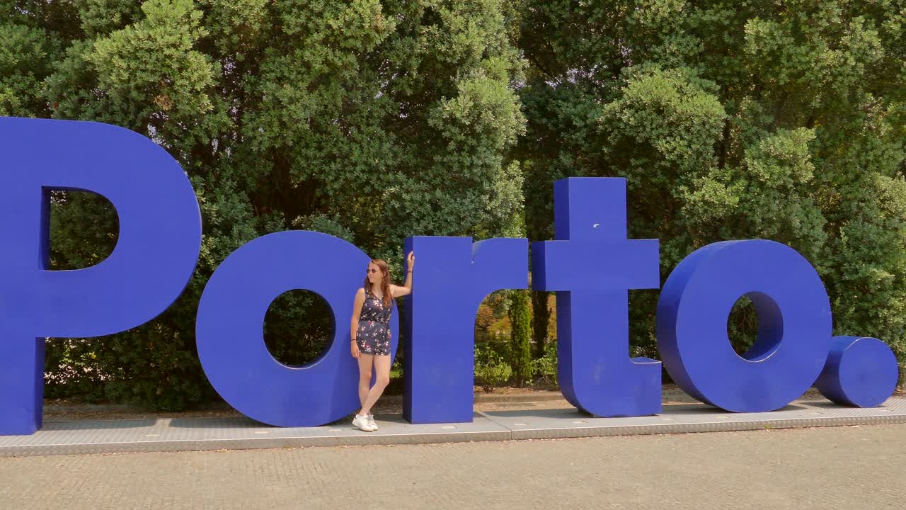 Tourist standing in front of a large sign establishing &amp;quot;Porto&amp;quot; in Portugal
