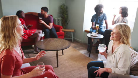 Two-young-women-sitting-in-the-lounge-room-at-a-pub,-holding-drinks-and-having-a-conversation,-elevated-view