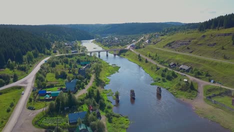 aerial view of a river, bridge, and village in a forest landscape