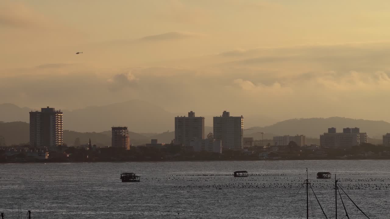 Penha's sunset skyline with distant high-rise buildings rising over calm Atlantic Ocean, Santa Catarina, Brazil