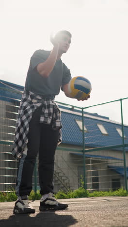 joven saltando voleibol al aire libre, con árboles y arena deportiva en el fondo, preparándose para un juego, demostrando atletismo y enfoque mientras se divierte bajo cielos brillantes