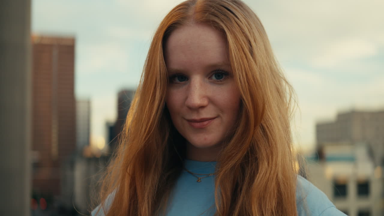 Portrait of a woman with red hair in front of a cityscape