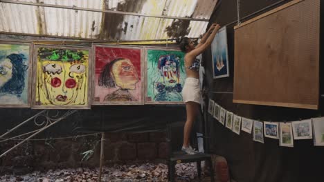 a south asian artist hanging paintings on the wall