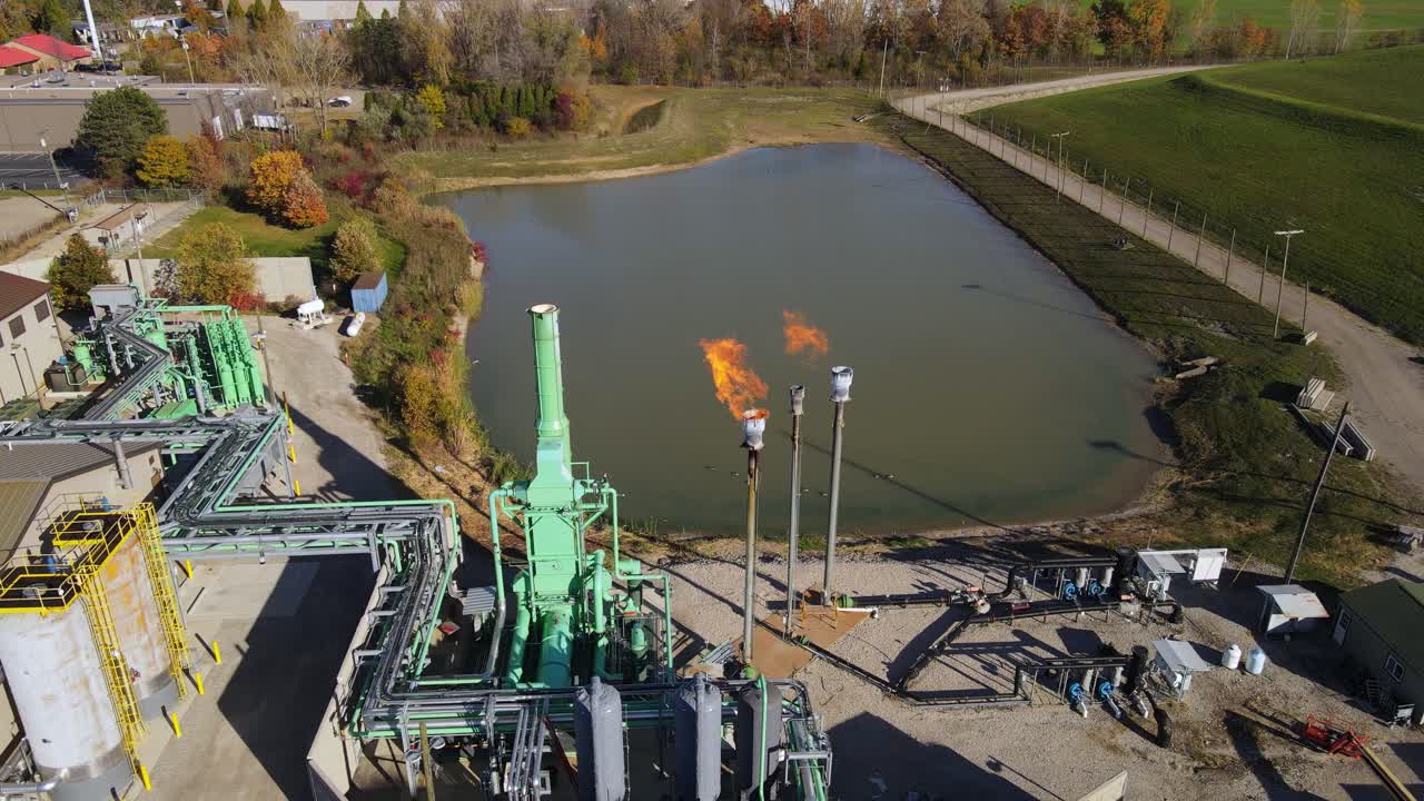 Aerial view of methane flare at landfill site with retention pond