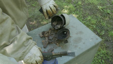 beekeeper filling smoker with dry bark fuel