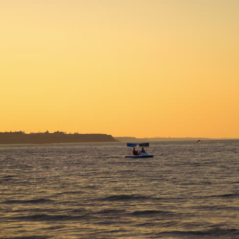 catamaran and people in the evening sea. blue boat floating on the background of the calm sea at sunset. people swimming in water.
