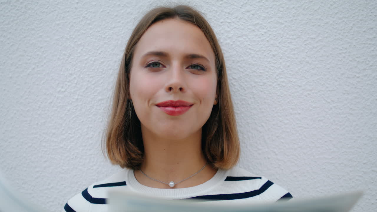 chica relajada leyendo el periódico en primer plano por la mañana. mujer sonriente mirando a la cámara