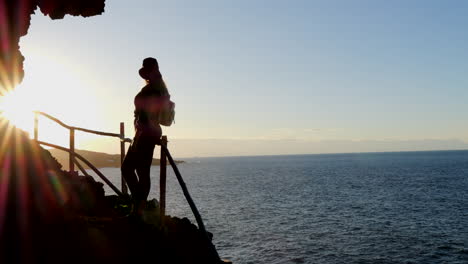 maravillosa foto de una mujer joven con sombrero admira durante la puesta de sol, el paisaje que se encuentra en la costa del municipio de galdar en la isla de gran canaria y durante la puesta de sol